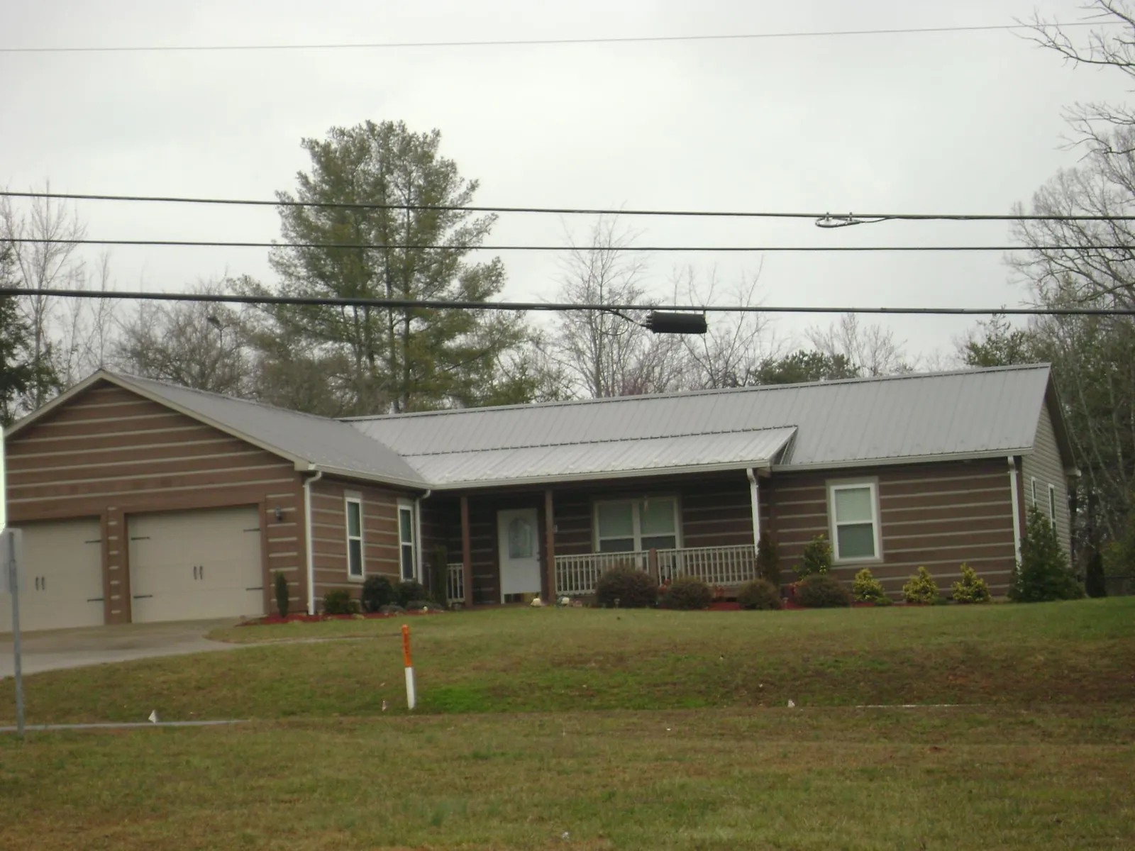 Gray metal roof on a log sided ranch home with a front porch in Hudson
